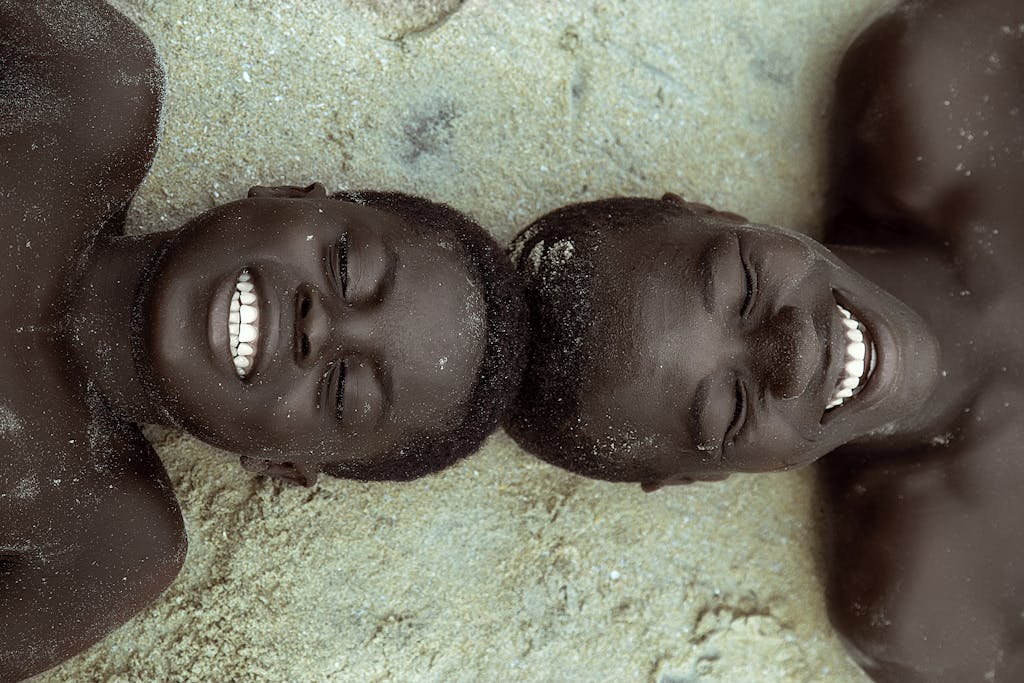 Top View of Two Boys Lying on the Ground with Their Head Touching and Smiling