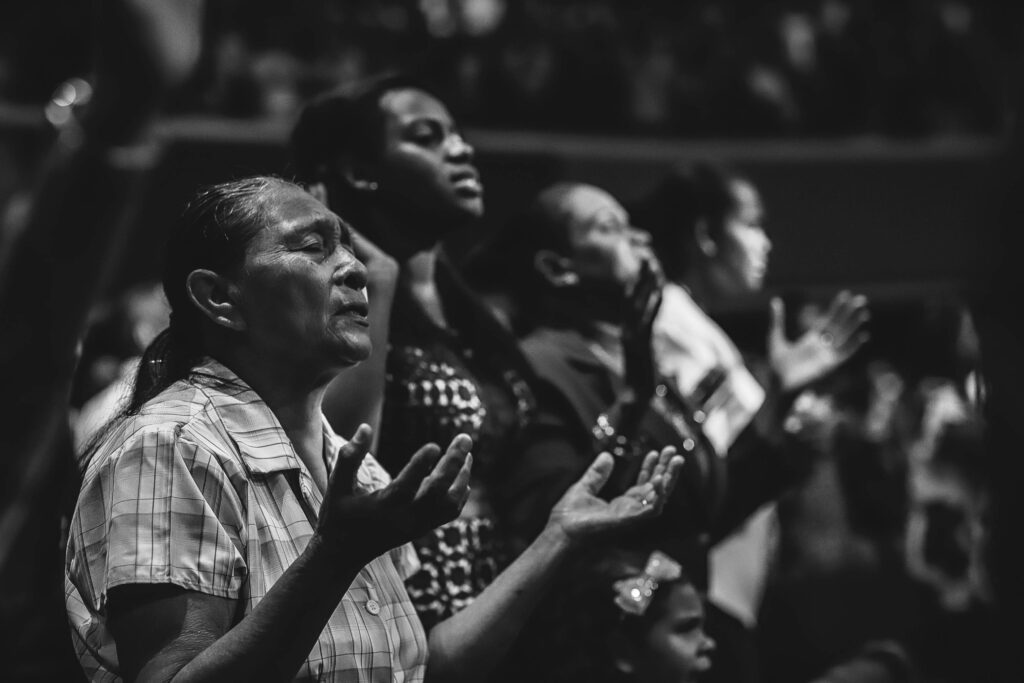 pexels-photo-2774576-2774576 Black and white image of a diverse group of people in prayer during a religious gathering.